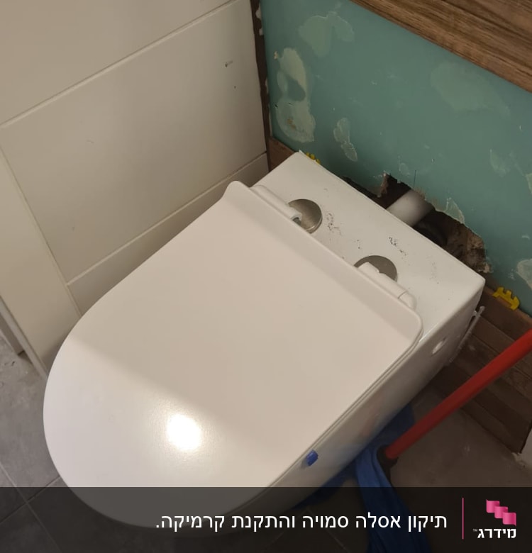 אסלה מותקנת עם מגבת כחולה וכלי עבודה אדום